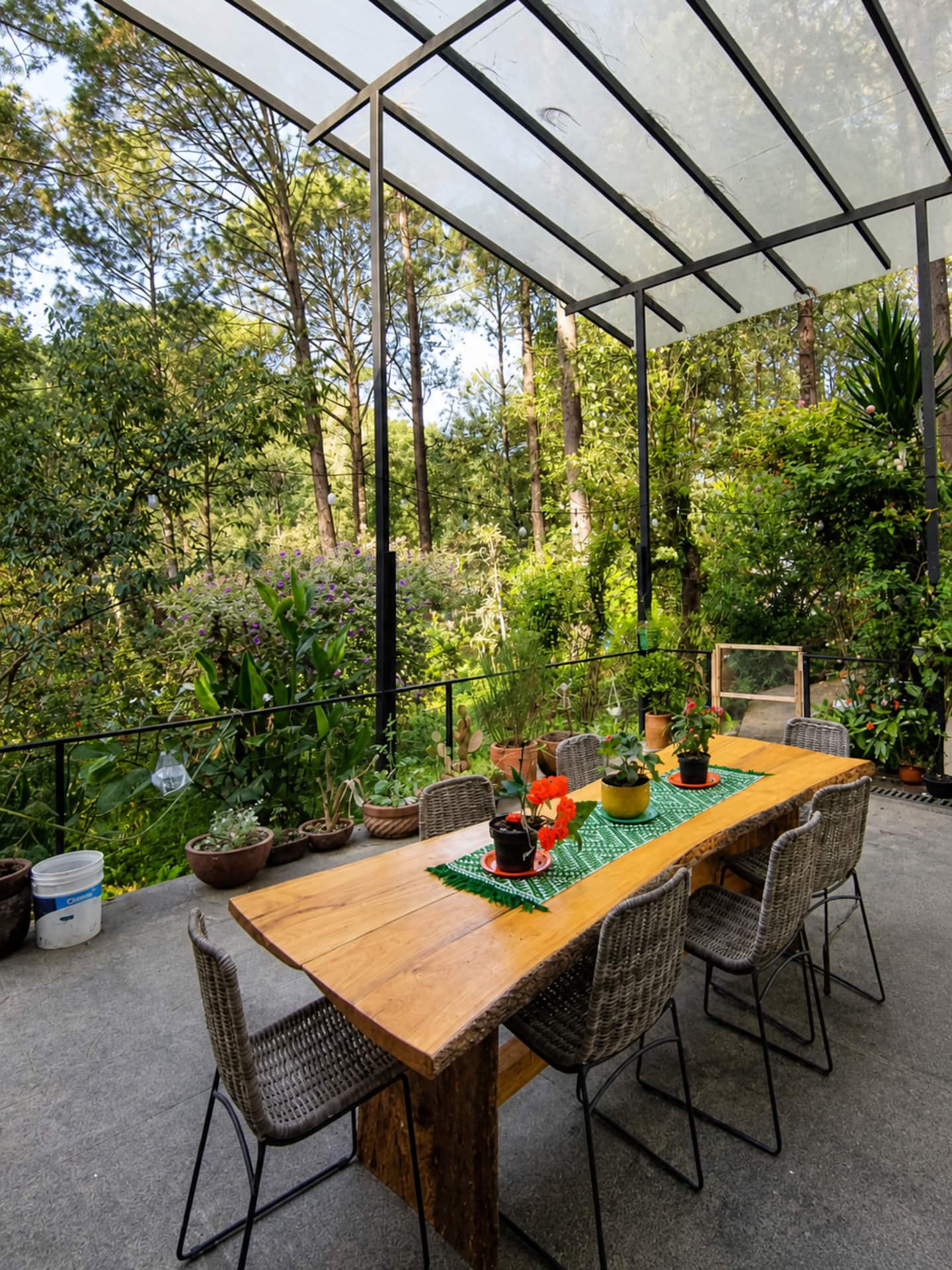 Mesa larga de madera en una terraza rodeada de árboles en Bosque Las Orquídeas