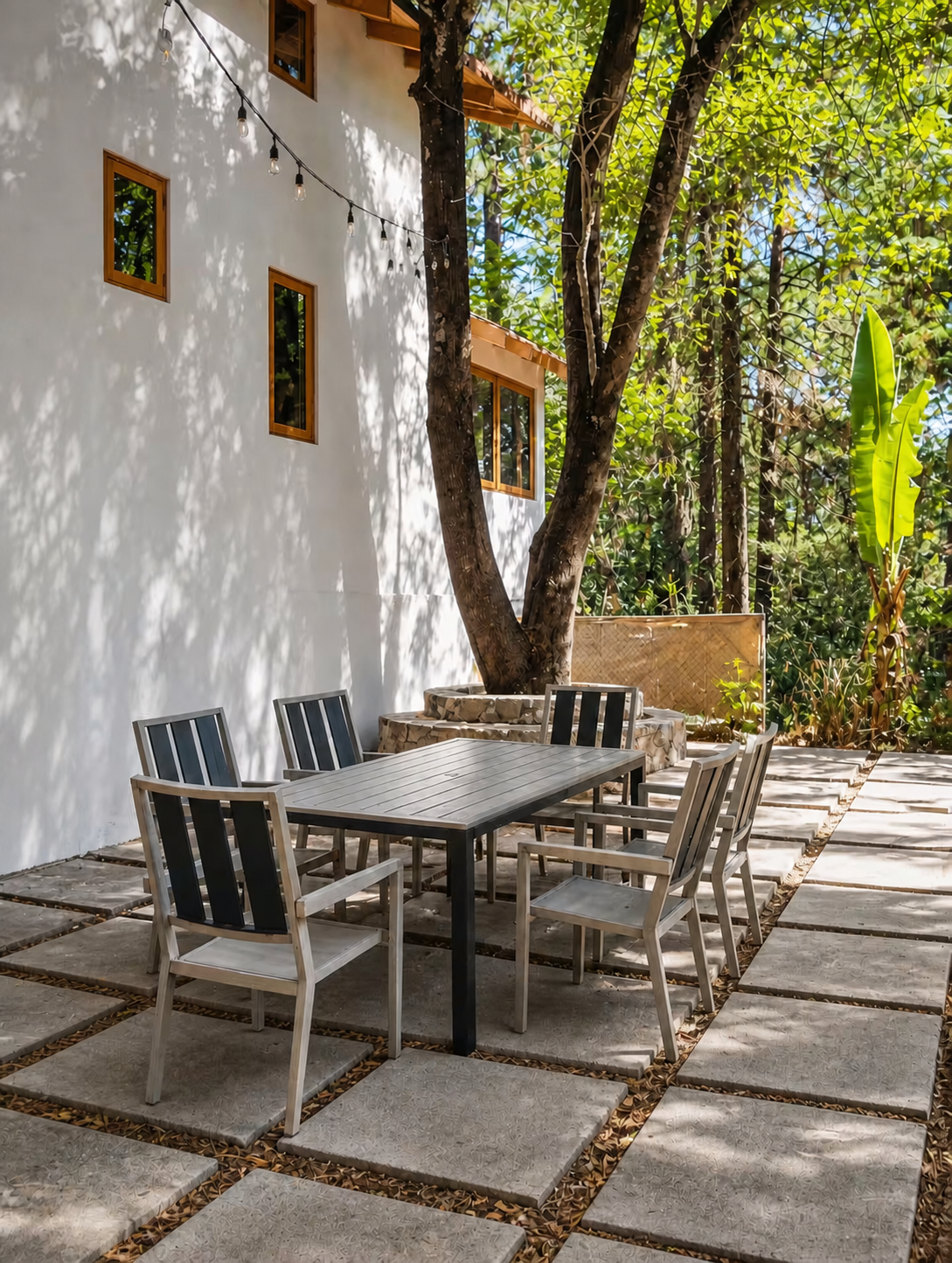 Mesa y sillas al aire libre junto a una casa bajo los árboles