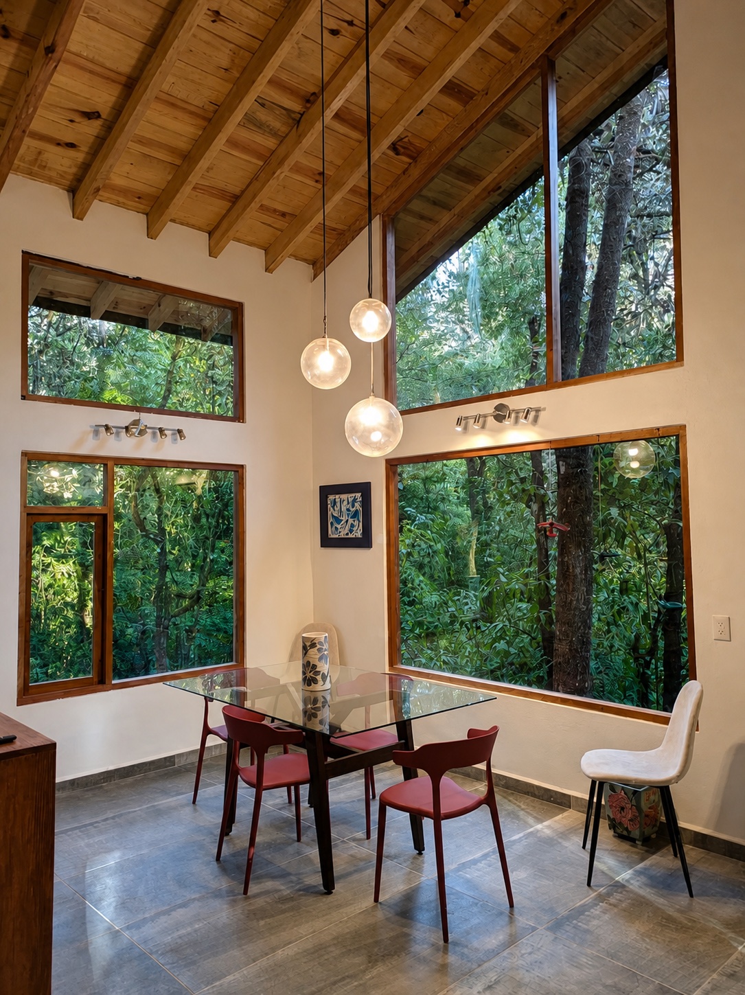 Comedor de techo alto con grandes ventanas hacia los árboles